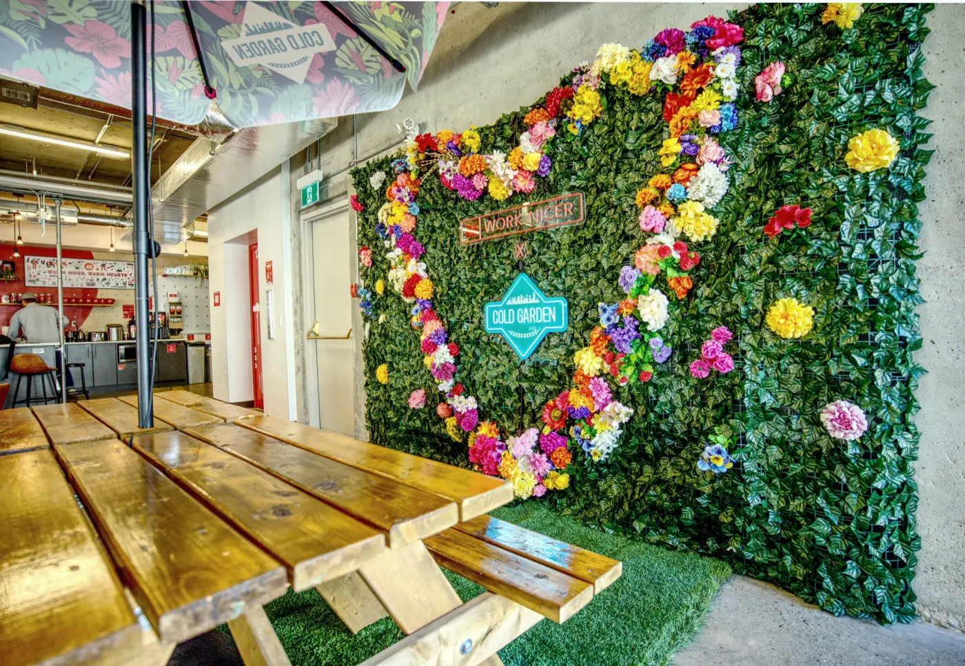 A picnic table on turf beneath the flower wall at Red Mile