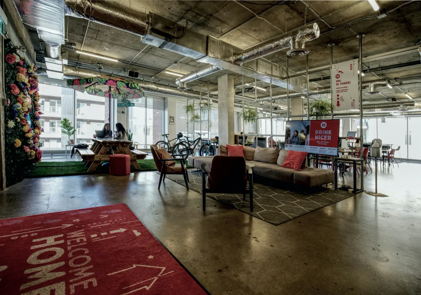 The lounge at Work Nicer Red Mile, with the flower wall and the welcome mat