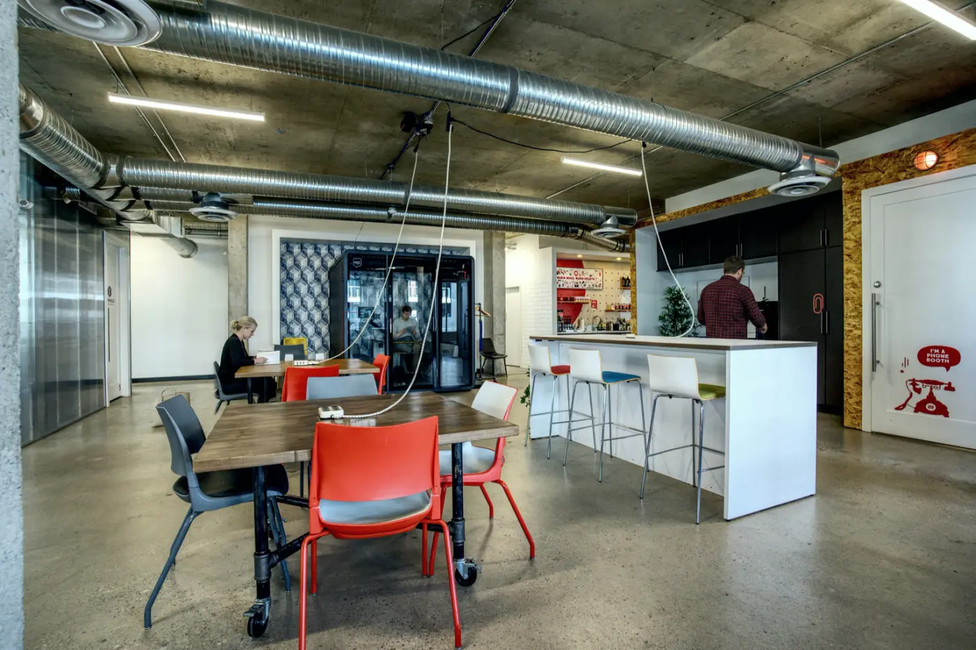 A meeting table with red chairs beside a counter at Red Mile