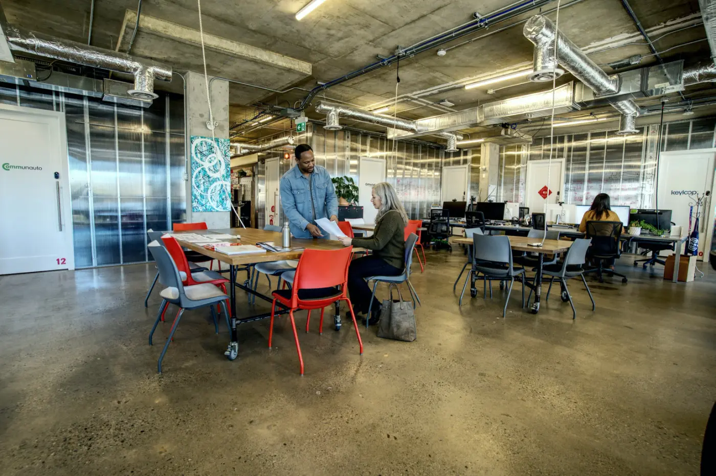 Two members talking at a table in the open seating at Work Nicer Red Mile