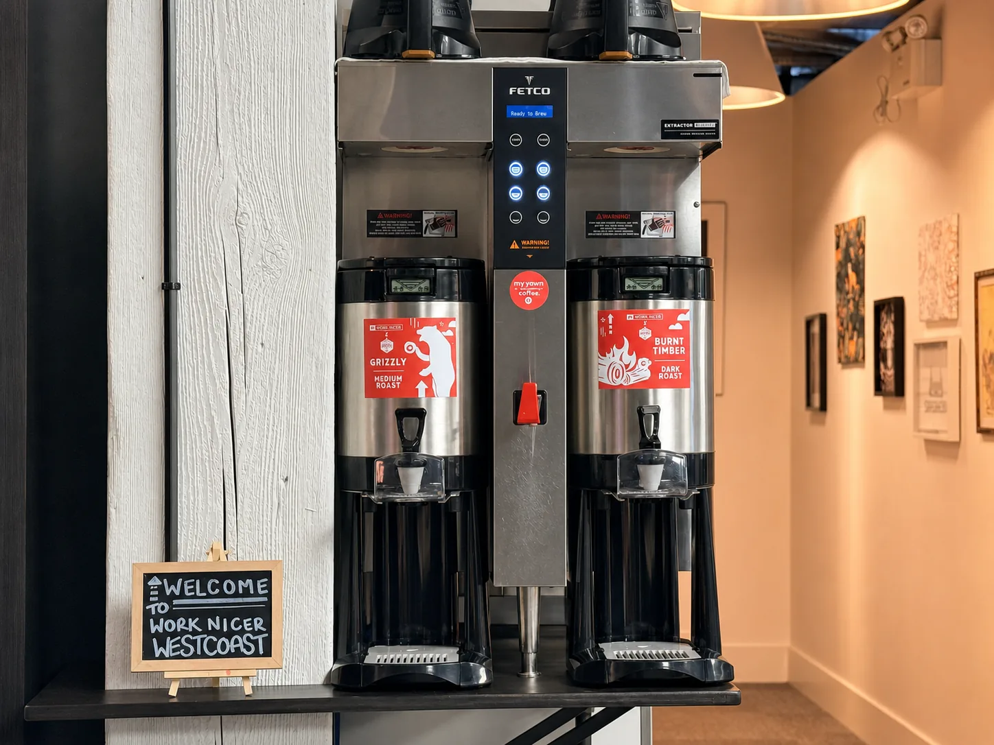 Two coffee brewers beside a chalkboard welcome sign at Westcoast